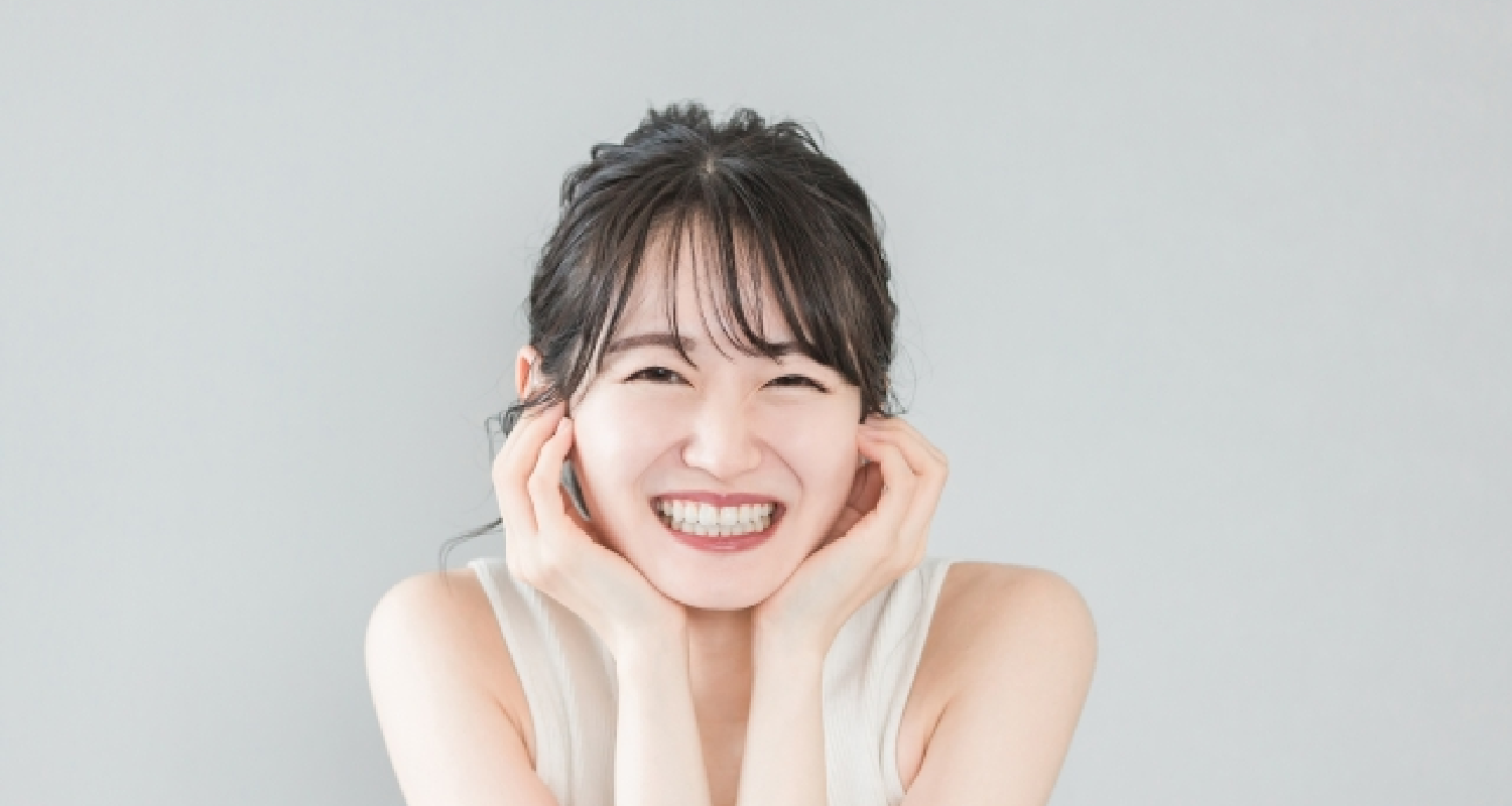 画像：歯を見せてほほ笑む女性